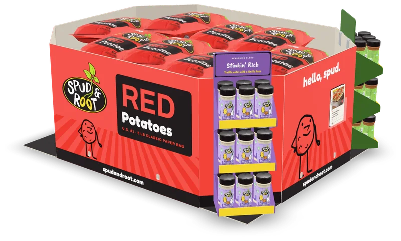 A Spud & Root bin of Red Potatoes: five-pound red paper bags inside a printed wrap, a shelf of Stinkin' Rich seasoning on its front corner, Herb Your Enthusiasm on the far corner and a recipe card in a pocket on its end.